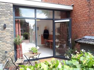 a conservatory with sliding glass doors in a brick building at Het Gindrahuis in Bladel