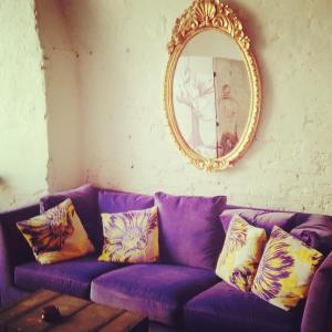 a purple couch with pillows and a mirror at Relais Alcova del Doge in Mira