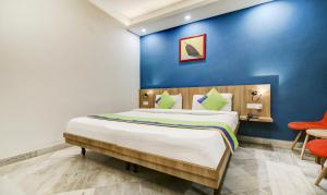 1 dormitorio con 1 cama grande y pared azul en Treebo Trend Mall View DLF Phase II en Gurgaon