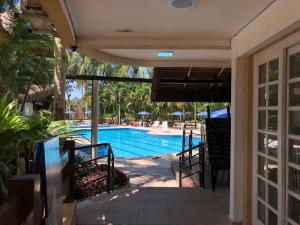 - une vue sur la piscine depuis la terrasse couverte d'une maison dans l'établissement Riviera de São Lourenço - Flat Amarilis, à Riviera de São Lourenço