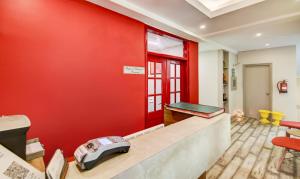 a red wall in a living room with a desk at Treebo Trend Mall View DLF Phase II in Gurgaon