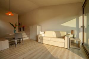 a living room with a white couch and a table at Residence Solemaremma in Castiglione della Pescaia