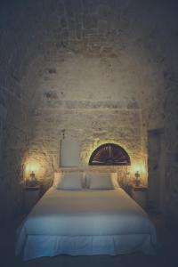 1 dormitorio con 1 cama blanca en una pared de piedra en Villa Amore Bianco, en Ostuni