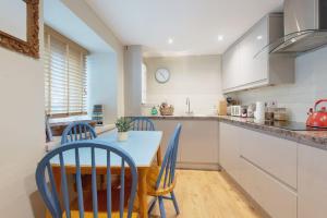 a kitchen with white cabinets and a table and chairs at The House on the Hill in Frome