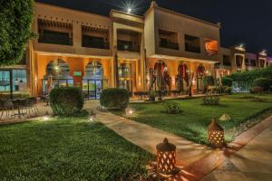 Zalagh Kasbah Hotel & Spa في مراكش: مبنى به انوار في العشب ليلا