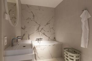 a bathroom with a white sink and a marble wall at Maris Apartments in Egmond aan Zee +36 photos