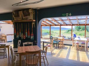 a dining room with tables and chairs and windows at YHA Broad Haven in Broad Haven