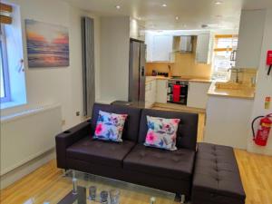 a living room with a brown couch and a kitchen at Spacious 2-bed apartment in central Kingston near Richmond Park in Kingston upon Thames