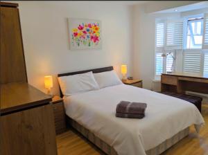 1 dormitorio con 1 cama blanca grande y piano en Spacious 2-bed apartment in central Kingston near Richmond Park, en Kingston upon Thames
