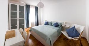 een slaapkamer met een bed met blauwe kussens en een stoel bij Paola's Home in Trieste