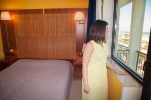 een vrouw in een hotelkamer die uit het raam kijkt bij Hotel Park in Sottomarina