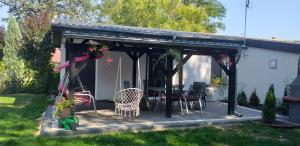 a pergola with chairs and tables in a yard at Domki w BOSZKOWIE in Boszkowo