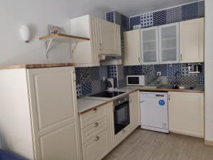 a kitchen with white cabinets and blue tiles on the wall at CARLETTO Los Angeles Los Cristianos in Los Cristianos