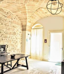 Habitación con mesa y pared de piedra. en Dimora Vico dei Nohi, en Lecce