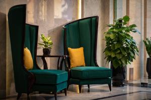 two green chairs in a room with a plant at Soleil Boutique Hotel Hanoi in Hanoi