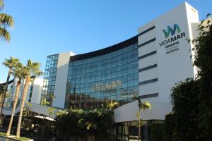 a view of a building with palm trees at VidaMar Resort Hotel Madeira - Dine Around Half Board in Funchal