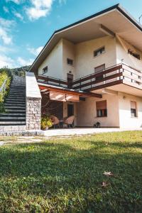 a house with a balcony and a grass yard at La Via Claudia Casa Vacanze in Valmareno