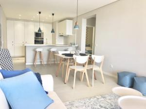 a living room and kitchen with a table and chairs at Apartamento Reis Magos in Caniço
