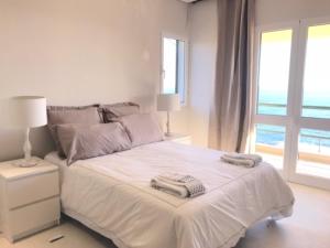 Un dormitorio blanco con una cama con toallas. en Apartamento Reis Magos, en Caniço