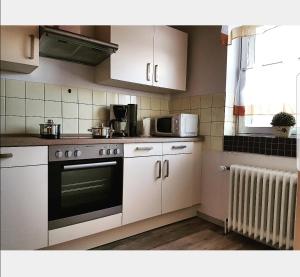 a kitchen with white cabinets and a stove top oven at Nordseebriese in Hage +8 photos