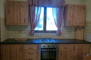 a kitchen with a stove and a window with curtains at Apartament BB Czarny Potok II in Krynica Zdrój