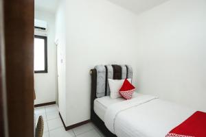 a small bedroom with a bed with a red pillow at Hotel O Bungo Guest House in Muarabungo