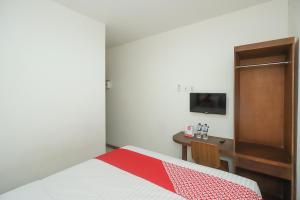 a bedroom with a bed and a desk with a television at Hotel O Bungo Guest House in Muarabungo +19 photos