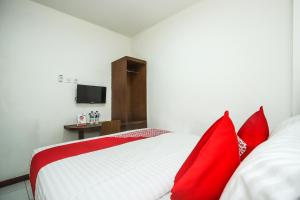 a bedroom with a red and white bed with red pillows at Hotel O Bungo Guest House in Muarabungo