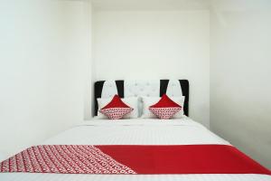 a bed with red and white pillows on it at Hotel O Bungo Guest House in Muarabungo