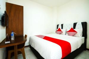 a bedroom with a bed with a desk and a television at Super OYO 1582 Bungo Guest House in Muarabungo