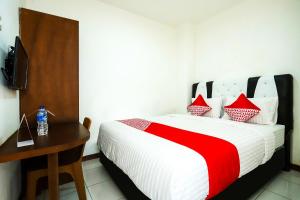 a bedroom with a bed with a desk and a television at Hotel O Bungo Guest House in Muarabungo