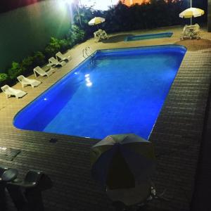 uma grande piscina azul com um guarda-sol ao lado em Hotel Guanabara em Caraguatatuba