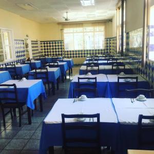 uma sala de jantar com mesas e cadeiras azuis em Hotel Guanabara em Caraguatatuba