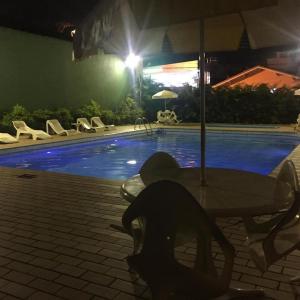 un hombre sentado en una mesa cerca de una piscina por la noche en Hotel Guanabara, en Caraguatatuba