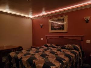 a bedroom with a bed and a painting on the wall at Deluxe Motel, Los Angeles Area in Downey