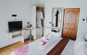ein Schlafzimmer mit einem Bett und einem TV sowie ein Zimmer in der Unterkunft Club Kaafu Maldives in Dhiffushi