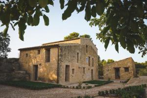 an old stone building with trees in the foreground at Casa rural Mas del Serranet in Horta de San Joan