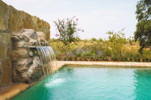 uma piscina com uma cascata numa parede de pedra em Casa rural Mas del Serranet em Horta de San Joan