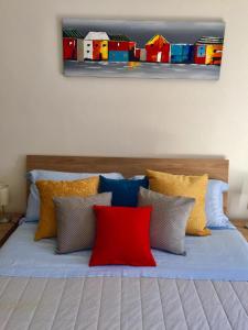 弗拉博薩索塔納的住宿－Casa Bianca，一张带色彩缤纷枕头的床和墙上的绘画