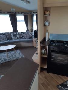een keuken en een woonkamer met een fornuis en een bank bij MV203 3 bedroom Deluxe caravan in Chapel Saint Leonards