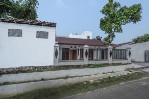 uma casa branca com um portão e escadas em Super OYO 1582 Bungo Guest House em Muarabungo