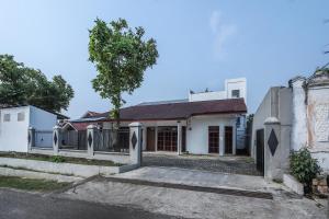una casa blanca con una puerta y un árbol en Super OYO 1582 Bungo Guest House, en Muarabungo