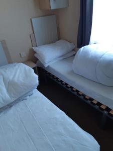 two twin beds in a room with a window at MV203 3 bedroom Deluxe caravan in Chapel Saint Leonards