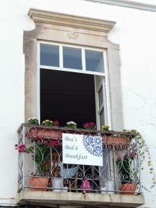a window with a blind and a sign on a balcony at Bea's Bed & Breakfast in Tavira