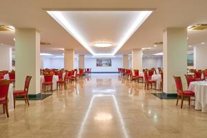 un salón de banquetes con mesas, sillas rojas y un registrador en Minerva Resort Hotel, en Paestum