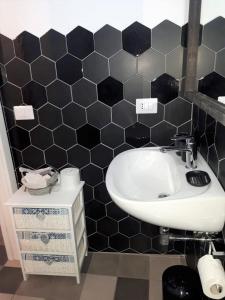 uma casa de banho com um lavatório e uma parede de azulejos pretos em Mary House em Belvedere Marittimo