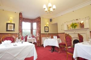 a dining room with two tables and a fireplace at The Tomich Hotel in Inverness