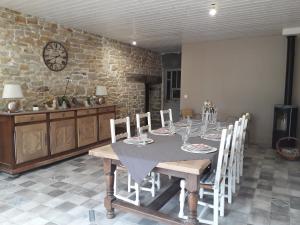 a dining room table with chairs and a clock on the wall at LES TROIS CHARMES in Chaucenne