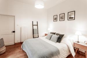 a white bedroom with a large bed and a desk at Au Coeur De La Ville in Honfleur