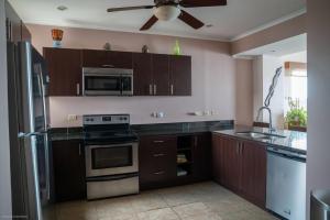 cocina con armarios marrones y ventilador de techo en The Palms Oceanfront Condo 604, en Jacó